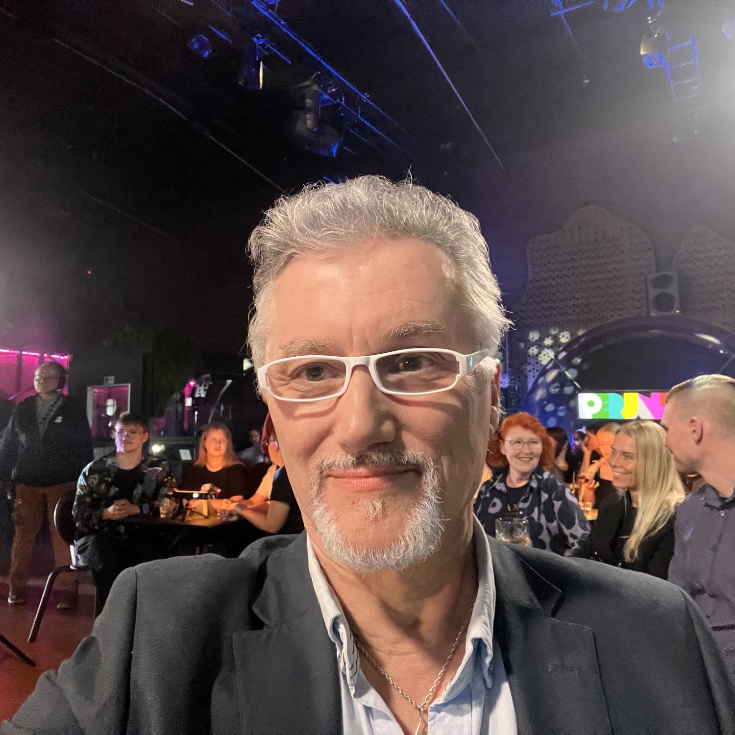 DJ facing a crowd at his deck. Photo with a purple hue